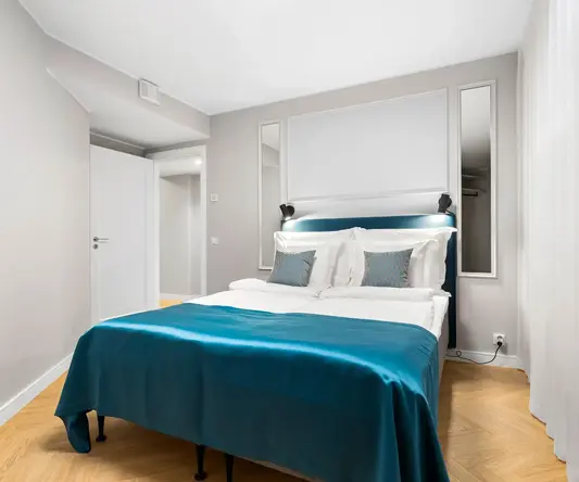 a bed with blue blanket and pillows in a room