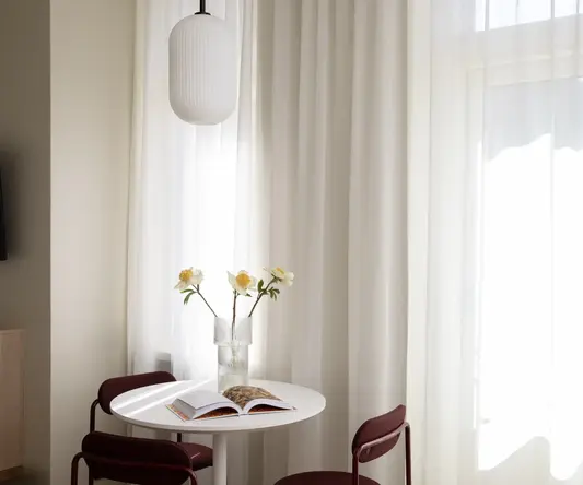 a table with chairs and a vase of flowers