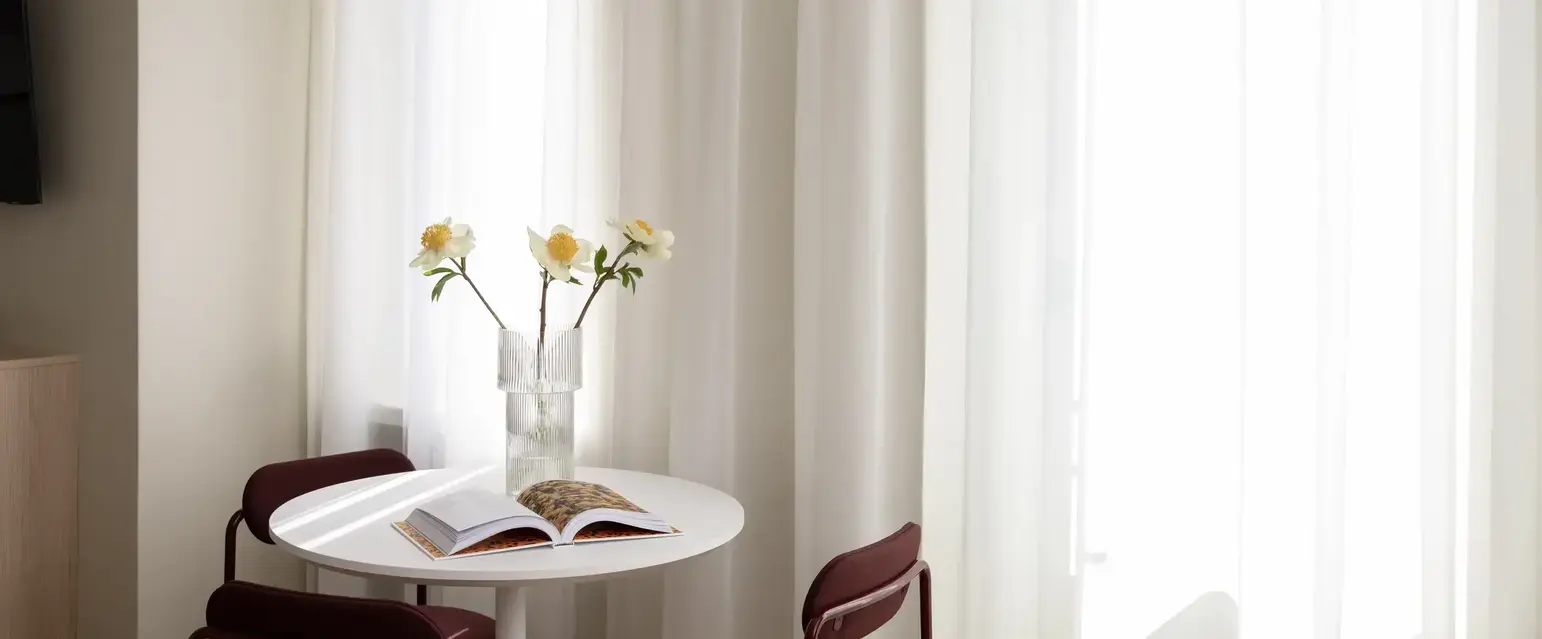 a table with chairs and a vase of flowers