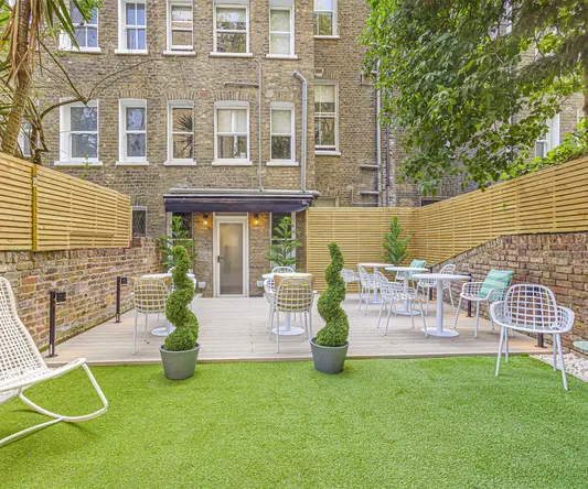 a patio area with chairs and tables in front of a brick building