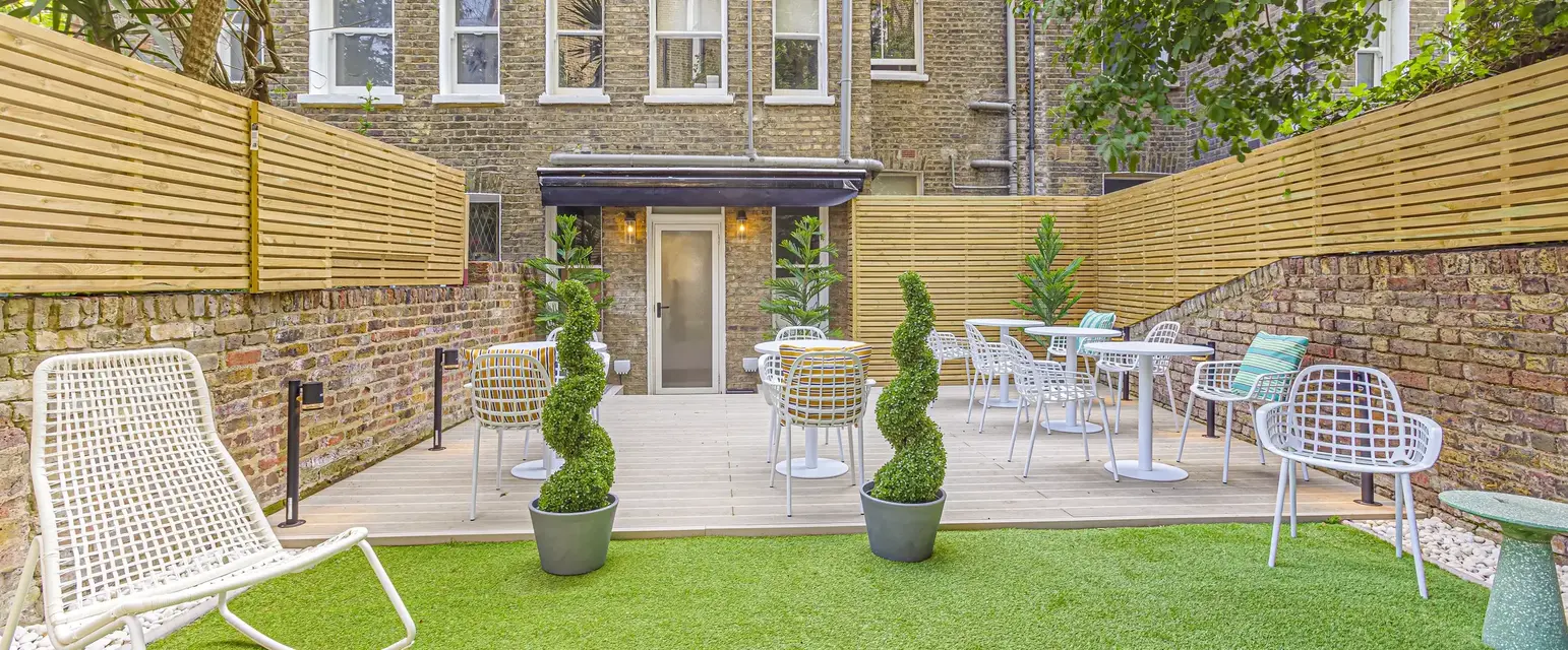 a patio area with chairs and tables in front of a brick building
