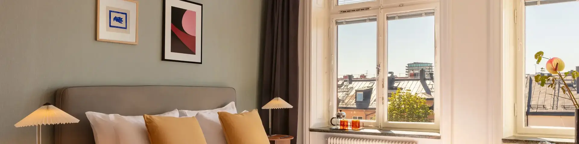 a bed with pillows and a lamp in a room with a window