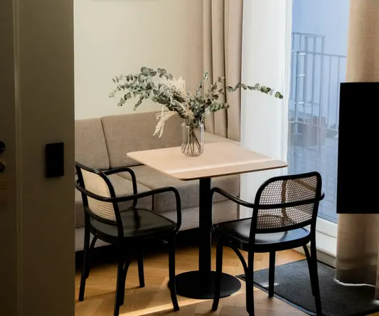 a table with chairs and a vase of flowers