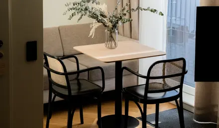 a table with chairs and a vase of flowers