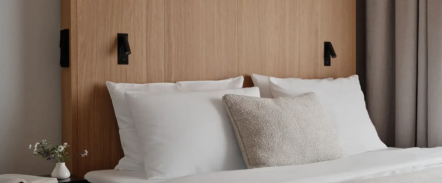 a bed with white pillows and a wood headboard