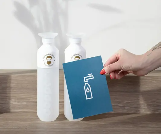 a hand holding a card next to two bottles