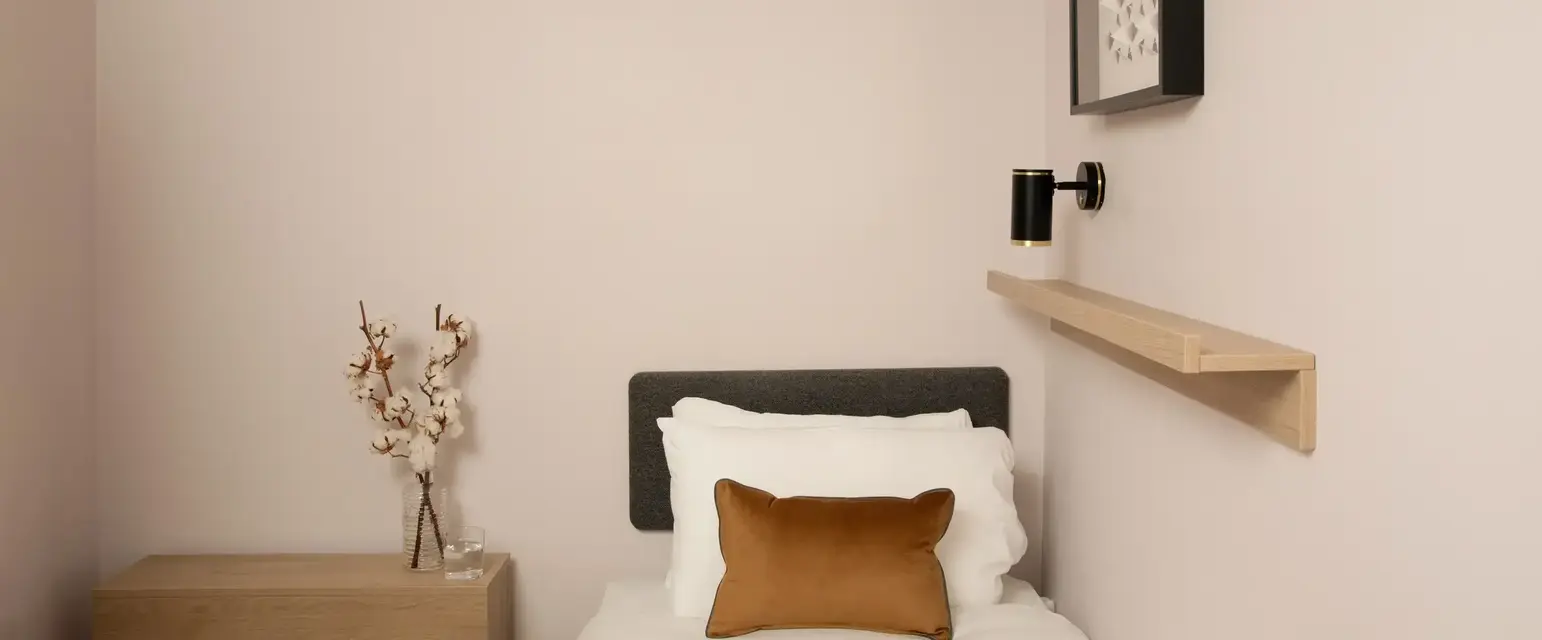 a small bed with a book and a brown pillow