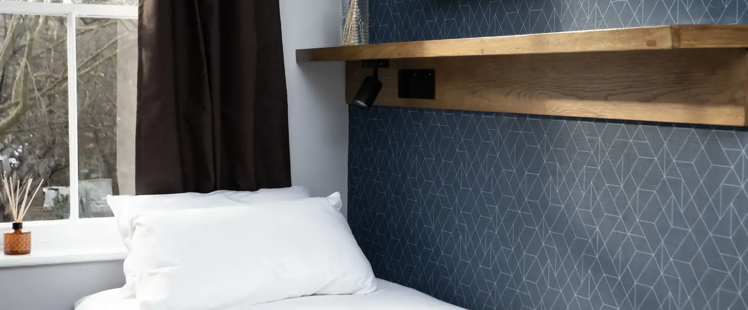 a bed with pillows and a shelf in a room