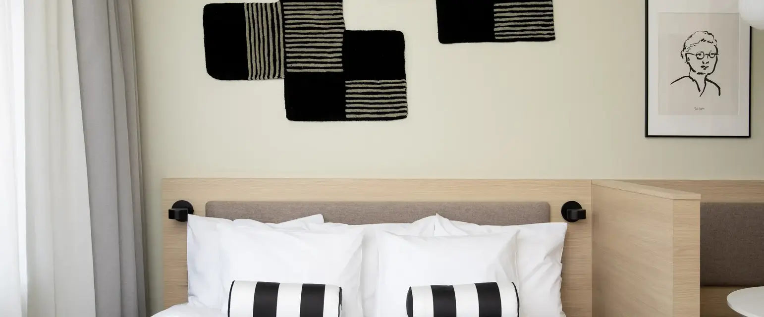 a bed with pillows and a black and white pillow on the headboard
