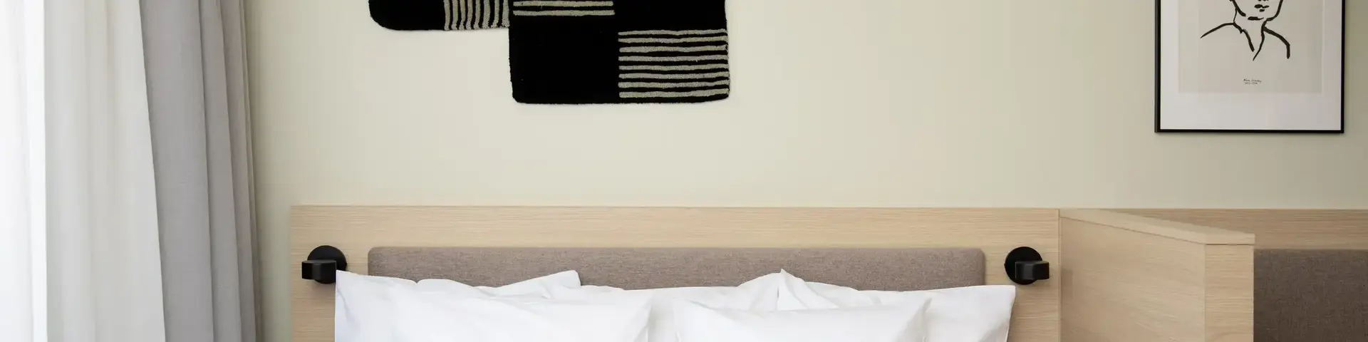 a bed with pillows and a black and white pillow on the headboard