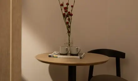 a table with a vase of red flowers and two mugs on it