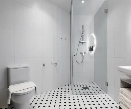 a bathroom with a glass shower and black and white checkered floor