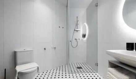 a bathroom with a glass shower and black and white checkered floor