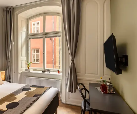 a room with a bed and a desk and a television