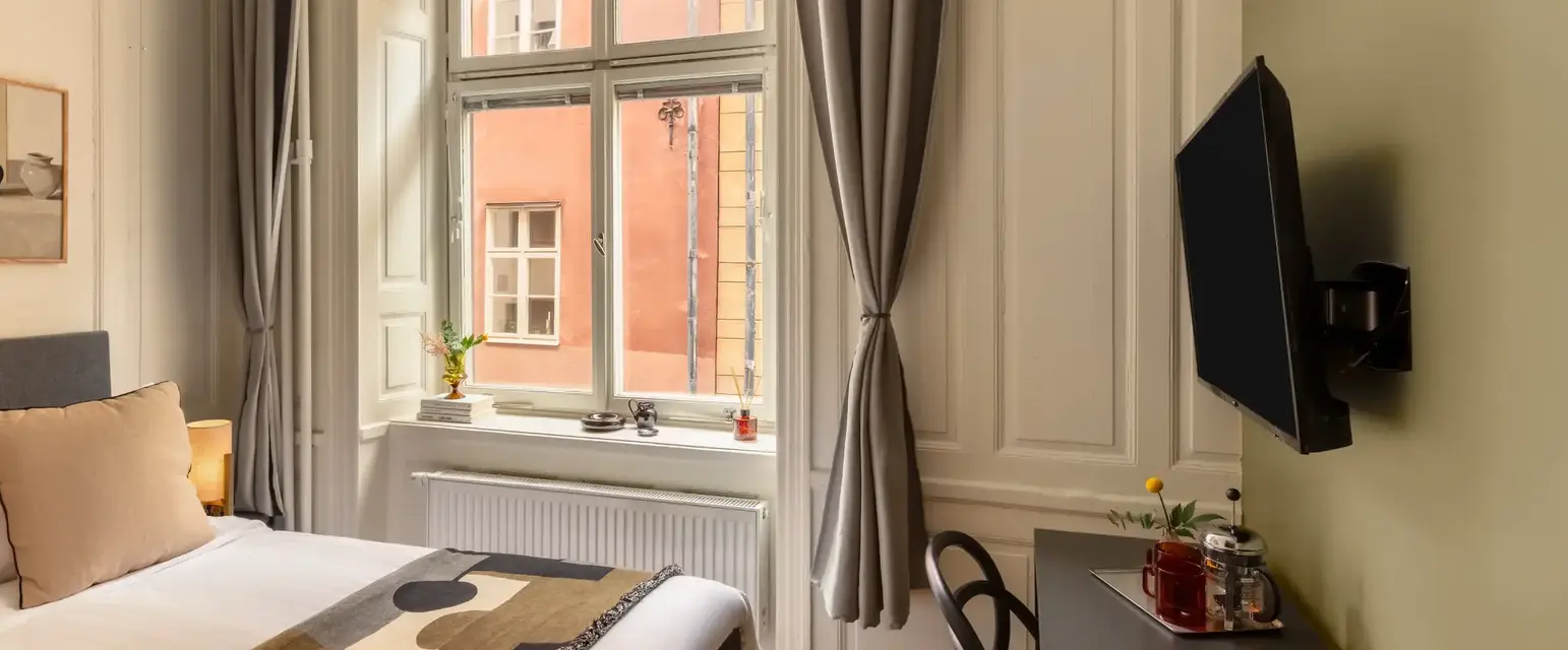 a room with a bed and a desk and a television