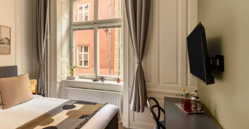 a room with a bed and a desk and a television