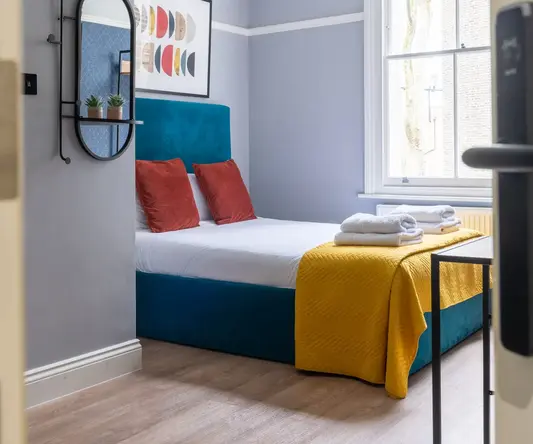 a bed with a yellow blanket and towels on it