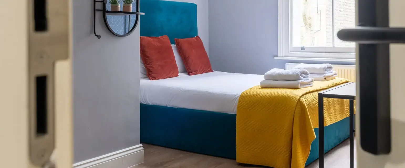 a bed with a yellow blanket and towels on it