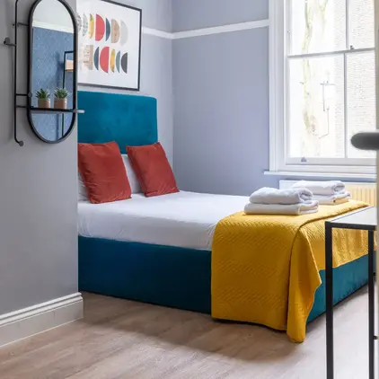 a bed with a yellow blanket and towels on it