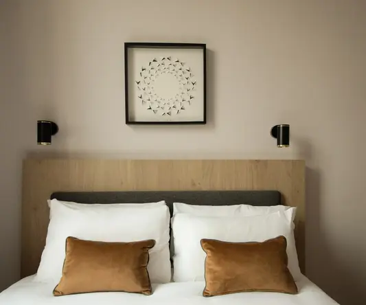 a bed with pillows and a picture on the wall