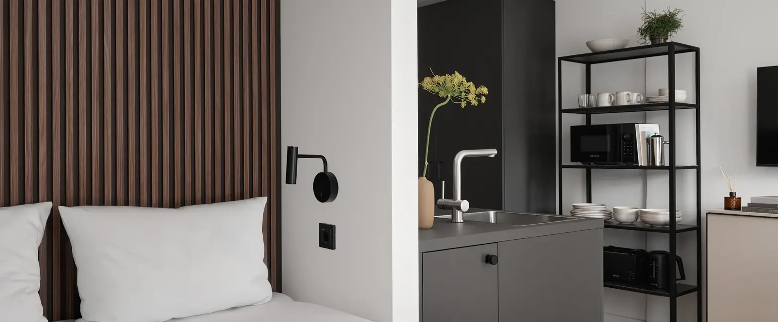 a bed with white sheets and a black shelf