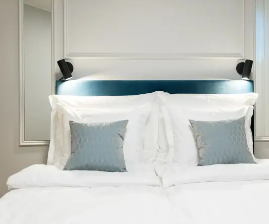 a bed with white sheets and blue pillows