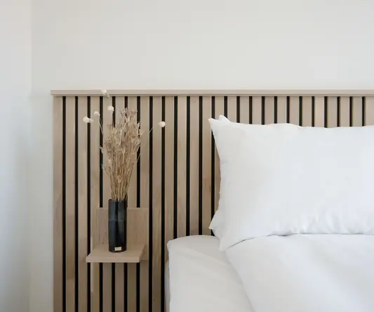 a vase of dried flowers on a bed