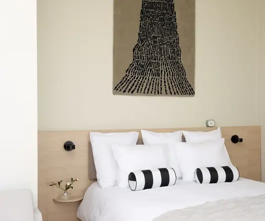 a bed with pillows and a piece of art on the wall