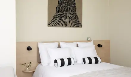 a bed with pillows and a piece of art on the wall