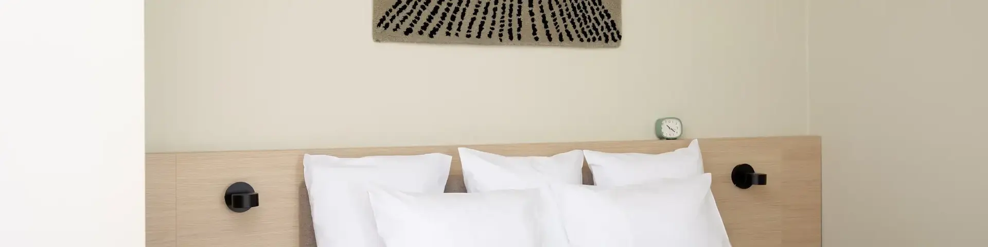 a bed with pillows and a piece of art on the wall