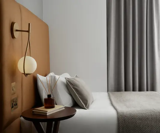 a bed with a lamp and a book