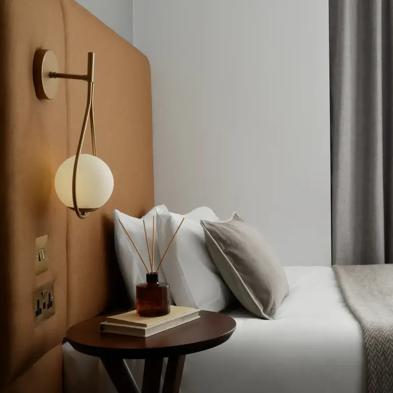 a bed with a lamp and a book