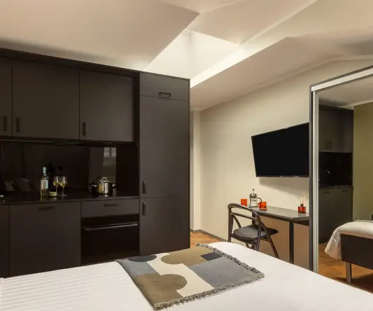 a room with a bed and a desk and a television