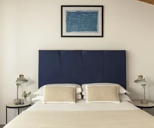 a bed with a blue headboard and a framed picture above it