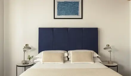 a bed with a blue headboard and a framed picture above it
