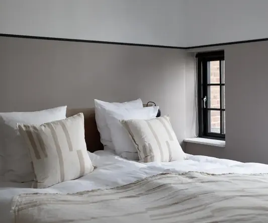 a bed with pillows and a window