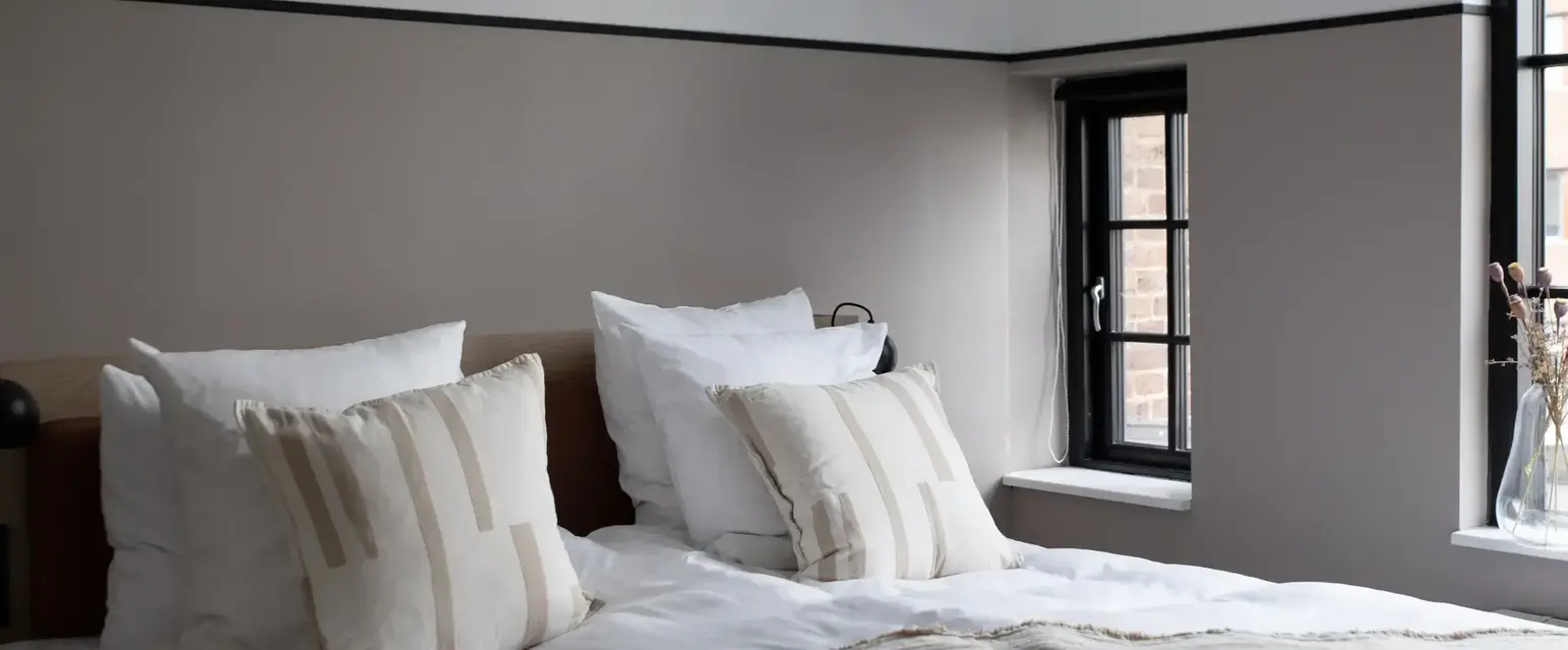 a bed with pillows and a window