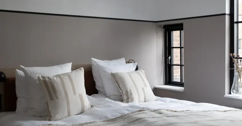 a bed with pillows and a window