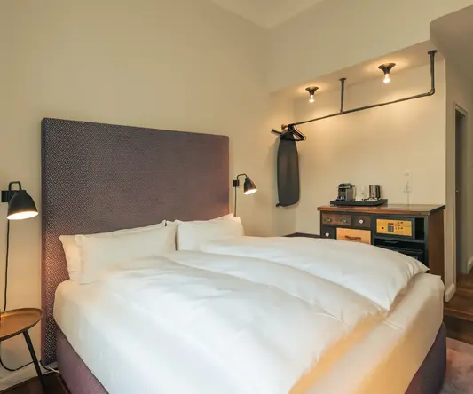 a bed with white sheets and a brown headboard