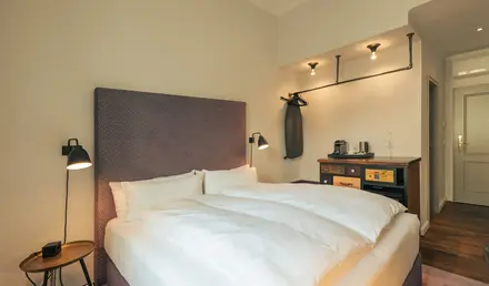 a bed with white sheets and a brown headboard