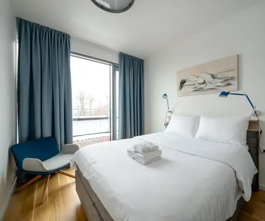 a bed with a white blanket and blue curtains