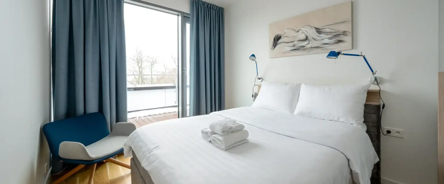 a bed with a white blanket and blue curtains