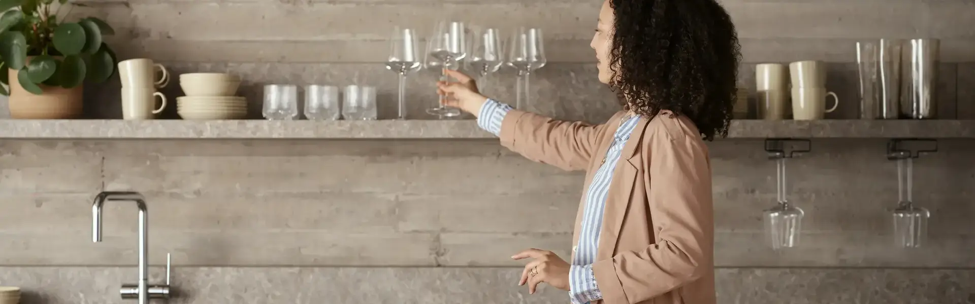 a woman holding wine glasses in a kitchen