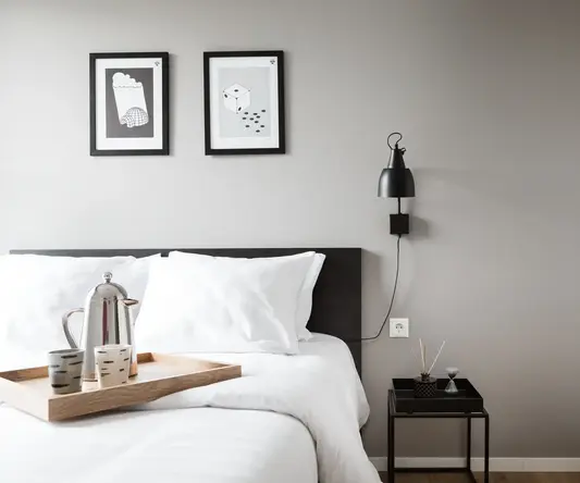 a bed with white sheets and a tray on the wall