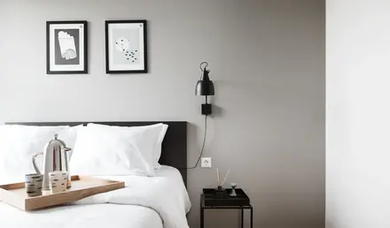 a bed with white sheets and a tray on the wall
