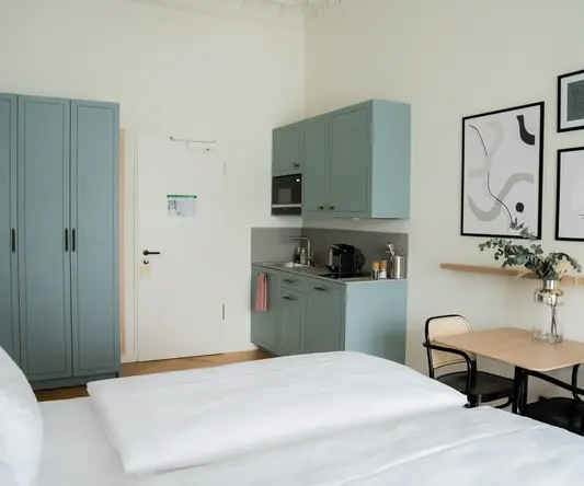 a room with two beds and a table and blue cabinets