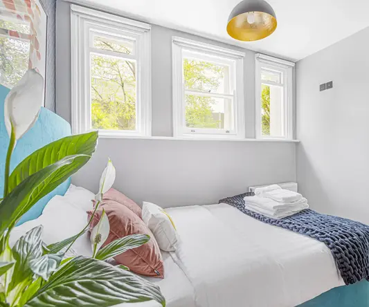 a bed with pillows and blankets in a room with windows