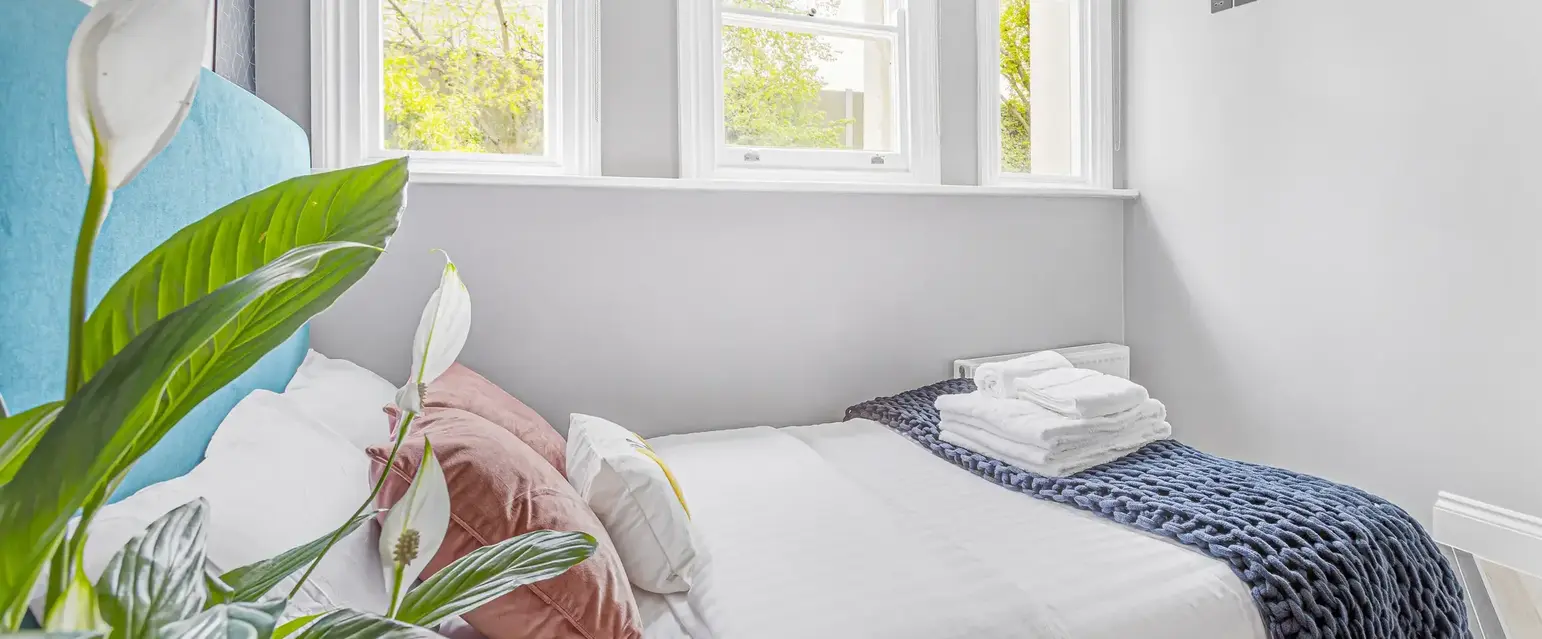 a bed with pillows and blankets in a room with windows