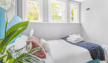 a bed with pillows and blankets in a room with windows