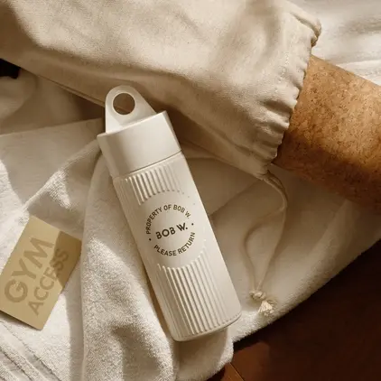 a white bottle next to a white towel